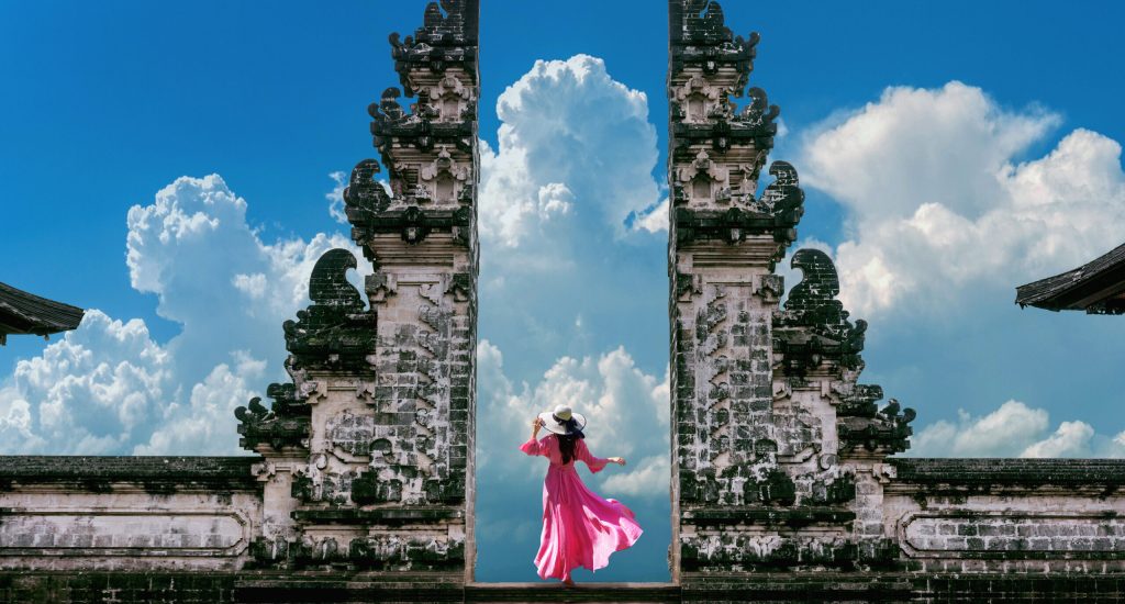 Young woman standing in temple gates at Lempuyang Luhur temple in Bali, Indonesia. Vintage tone.