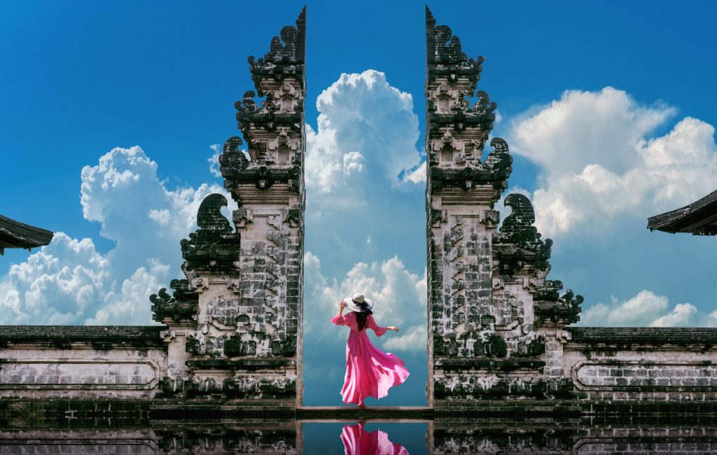 Young woman standing in temple gates at Lempuyang Luhur temple in Bali, Indonesia. Vintage tone.